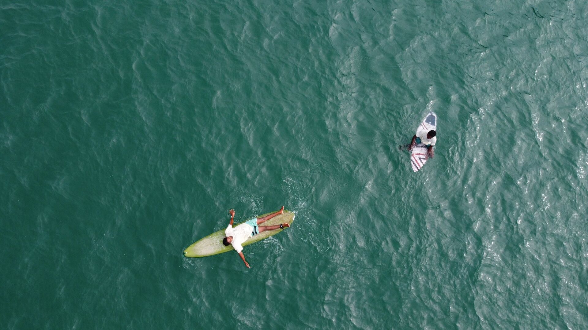 Aerial drone shot of surfers in turquoise water at Weligama